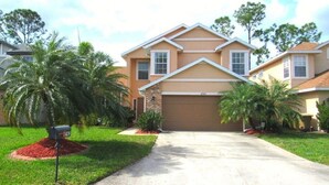 A two-story house with a garage, surrounded by well-maintained lawns and palm trees. - Ref 43 Family Villa With own Pool Near Disney (Kissimmee)