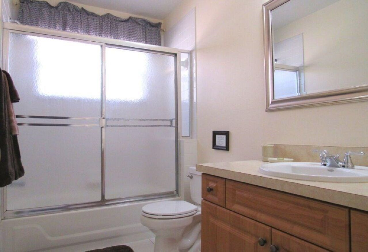 A bathroom with a shower, toilet, vanity, and sink.