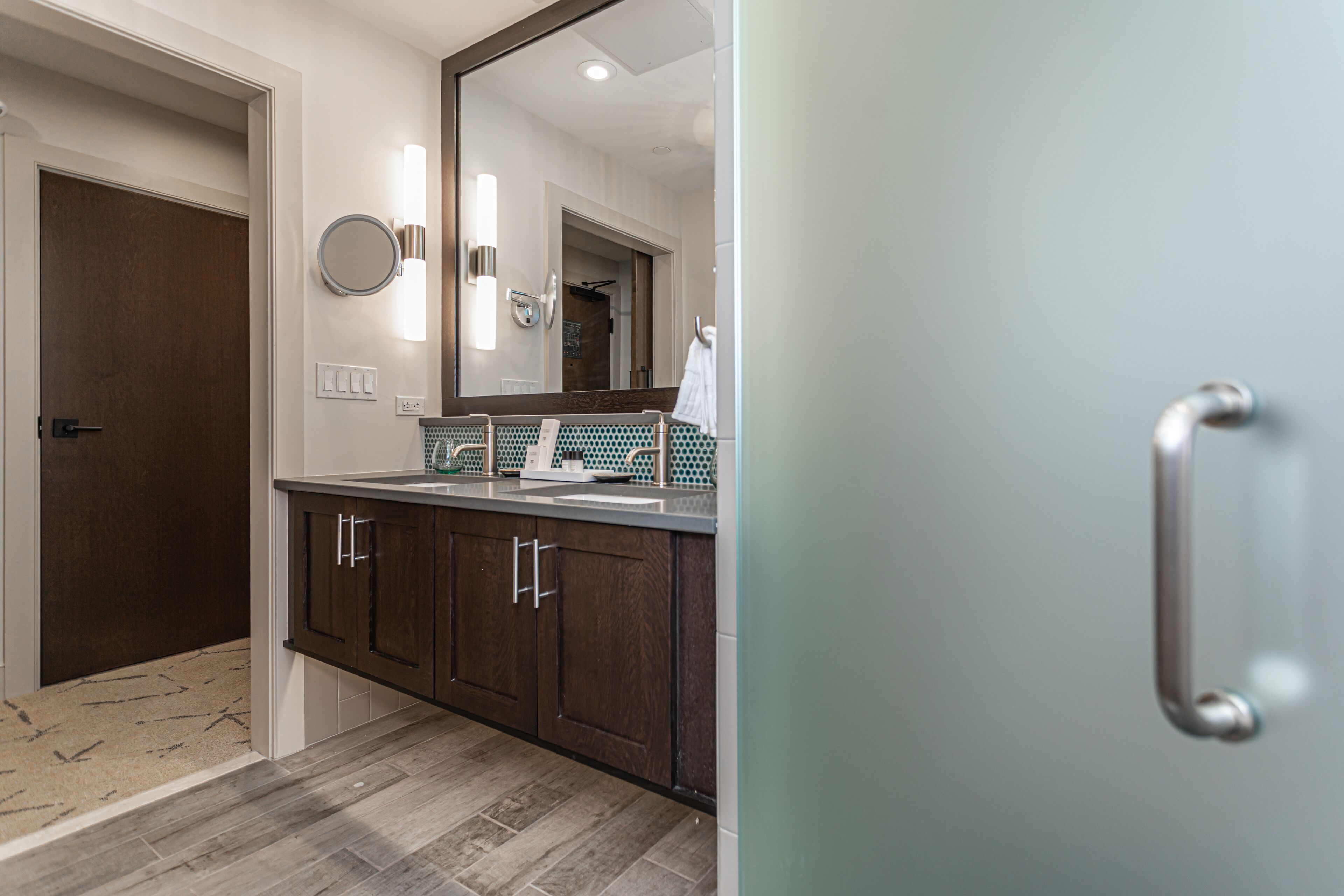 A modern bathroom with a wooden vanity, a large mirror, and a towel rack.