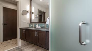 A modern bathroom with a wooden vanity, a large mirror, and a towel rack.