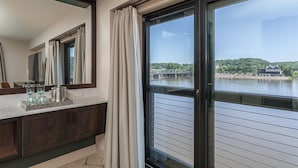 A bathroom with a large mirror, a vanity with a sink, and a window overlooking a lake. - Ghost Light Inn (New Hope)