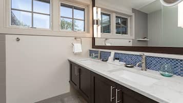 A modern bathroom with two sinks, dark wooden cabinets, a large mirror, and a blue-tiled backsplash.