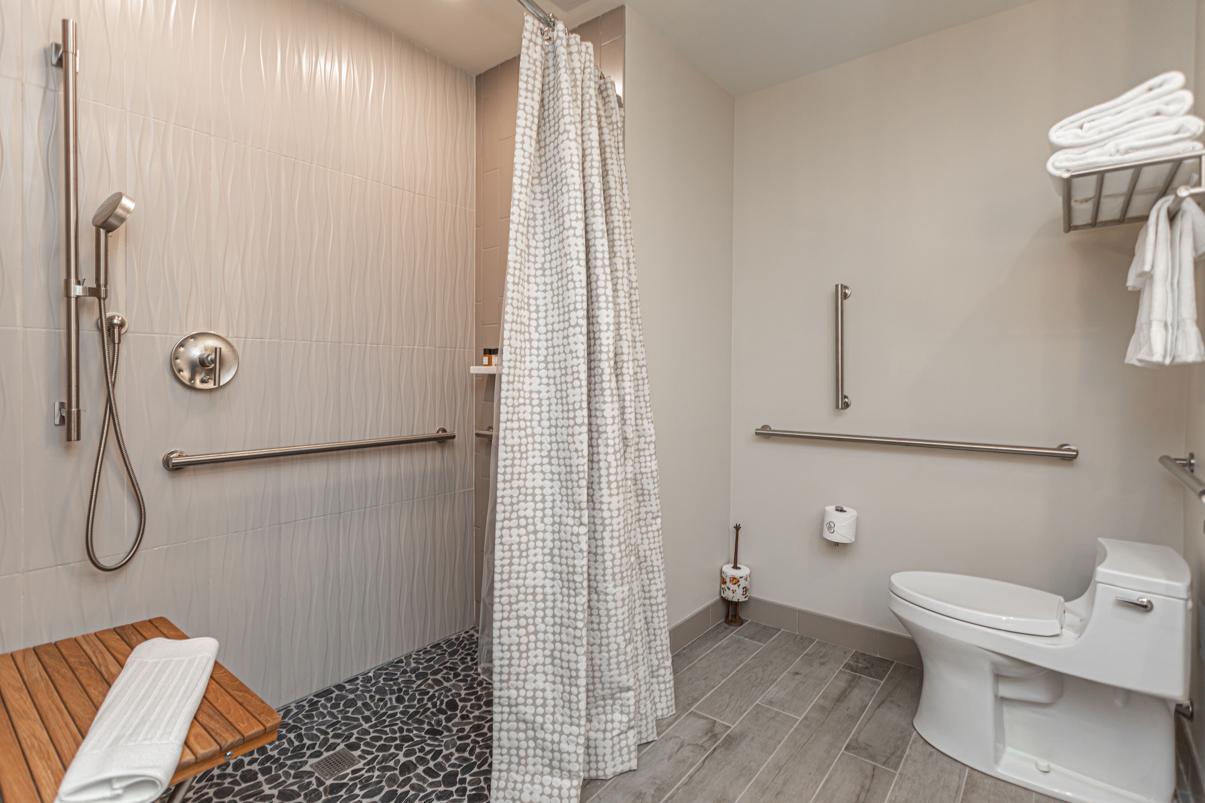 Et moderne badeværelse med bruser, toilet og håndklædestang.
