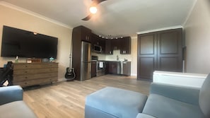 A modern kitchen with dark cabinets, a stainless steel refrigerator, and a microwave.