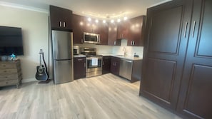 Una cocina moderna con electrodomésticos de acero inoxidable, armarios de madera oscura y piso de madera clara.