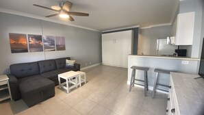 Un appartement moderne comprenant un salon, une kitchenette et un ventilateur de plafond.