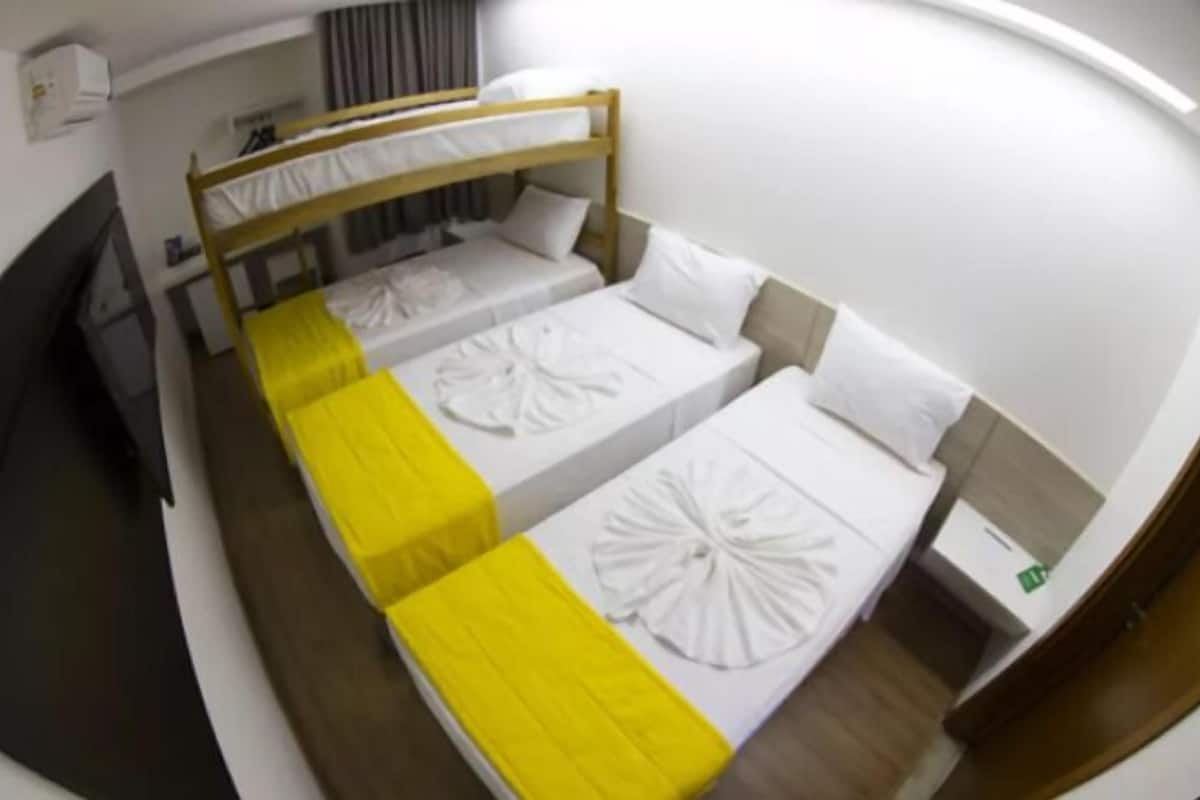 Une chambre d’hôtel avec deux lits simples, une tête de lit en bois, une télévision et une petite table de chevet.