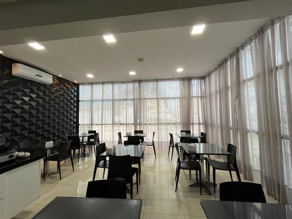 Un comedor moderno con mesas y sillas, una encimera de cocina y una pared con diseño.