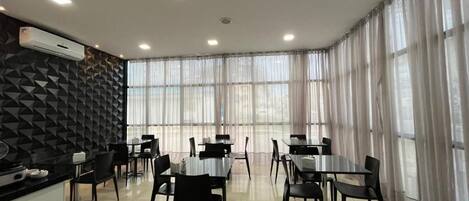 Un comedor moderno con mesas y sillas, una encimera de cocina y una pared con diseño.