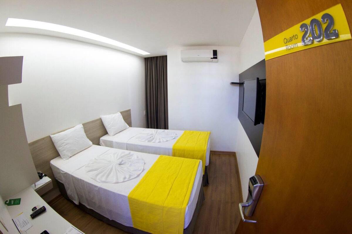 Une chambre d’hôtel avec deux lits, un bureau, une télévision et un appareil de climatisation.
