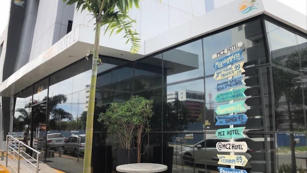 Un hotel moderno con facciata in vetro e insegna che indica le distanze da diversi luoghi.
