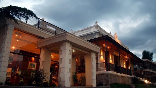 A hotel with a covered entrance, large windows, and a balcony. - Hotel Montecassino (Capilla del Monte)