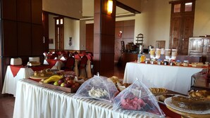 A buffet setup with various food items and a dining area with red chairs. - Hotel Montecassino (Capilla del Monte)