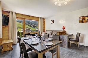 A dining area with a table set for four, a sofa, and a TV mounted on the wall.