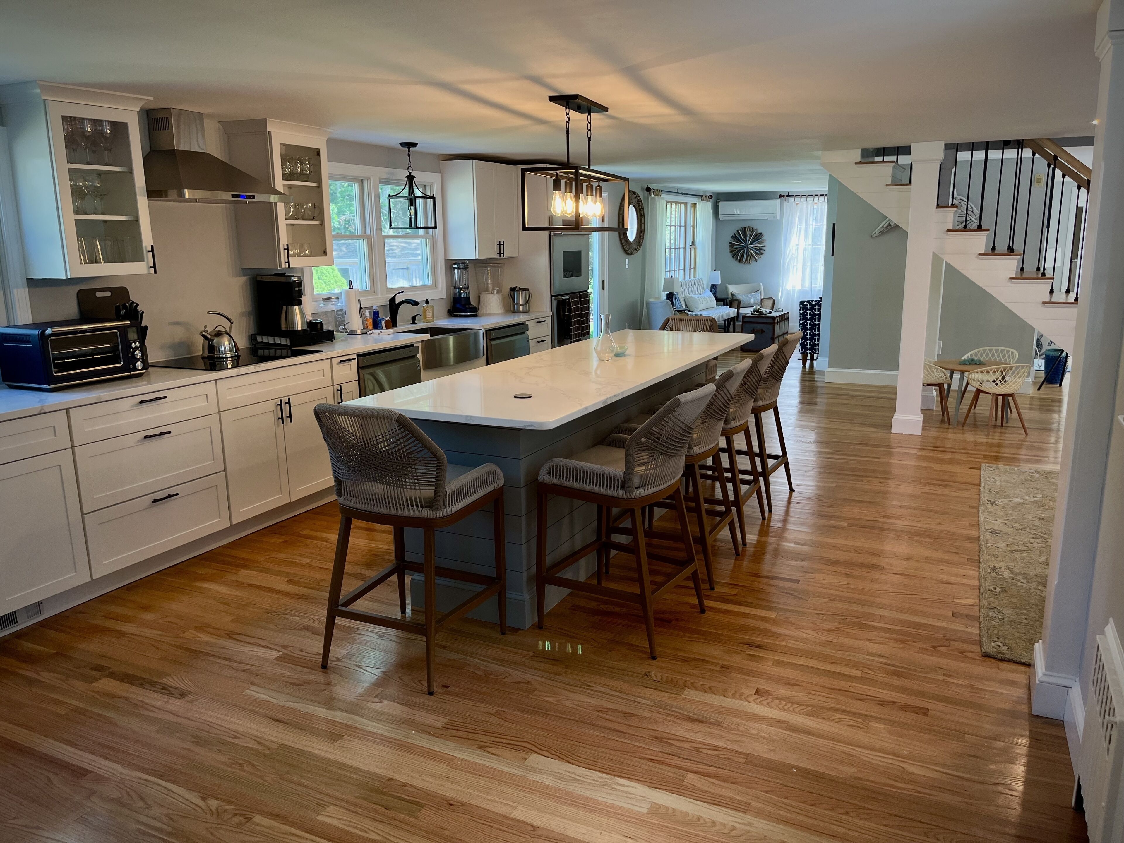 Een ruime keuken met een groot eiland, houten vloeren en moderne apparatuur.