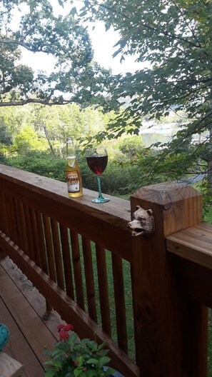 Een houten terras met een glas rode wijn en een fles Corona Light bier.