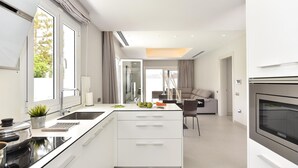 Una cuina moderna amb una illa central, una zona de menjador amb un sofà i vista a l'exterior.