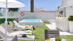 Zona de piscina amb gandules, ombrel·les i zona de menjador amb plats, gots i pomes.
