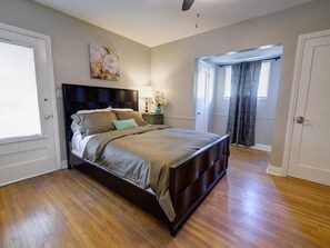 A bedroom with a large bed, a nightstand, a lamp, and a painting on the wall.