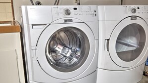 A front view of a white, two-door washing machine with control panels and a transparent door.