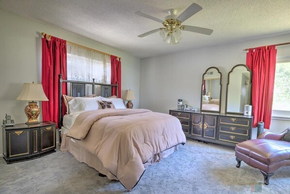 A bedroom with a bed, nightstands, a dresser, a mirror, and a chair.