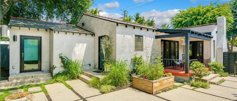 Ein modernes Haus mit überdachter Terrasse, kleinem Garten und Garage.