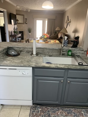 A kitchen with a built-in dishwasher, a sink, and a countertop with various items.