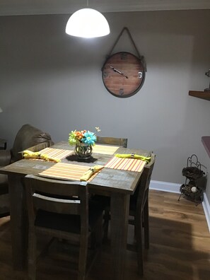 Een eethoek met een houten tafel, stoelen en een wandklok.