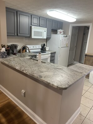 A kitchen with grey cabinets, a white stove, and a white refrigerator. - Beautiful condo next to Golf course (Pigeon Forge)