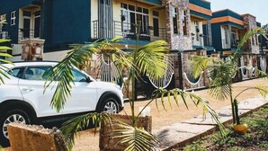 A modern residential building with a blue and orange facade, multiple balconies, and a white car parked in front. - Konga Hotel Kigali (Kigali)