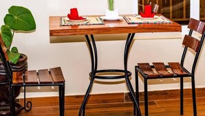 A dining area with a wooden table, two chairs, a vase with flowers, and a potted plant. - Konga Hotel Kigali (Kigali)