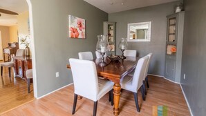 A dining area with a wooden table, white chairs, and a ceiling fan.