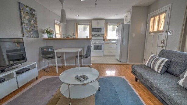 A compact living space with a sofa, TV, dining table, and kitchenette. - The Willows (Pasadena)