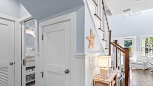 A hallway with a white door, a wooden staircase, and a white sofa in the background. - Luxury Watersound Getaway with Golf Cart (Watersound)