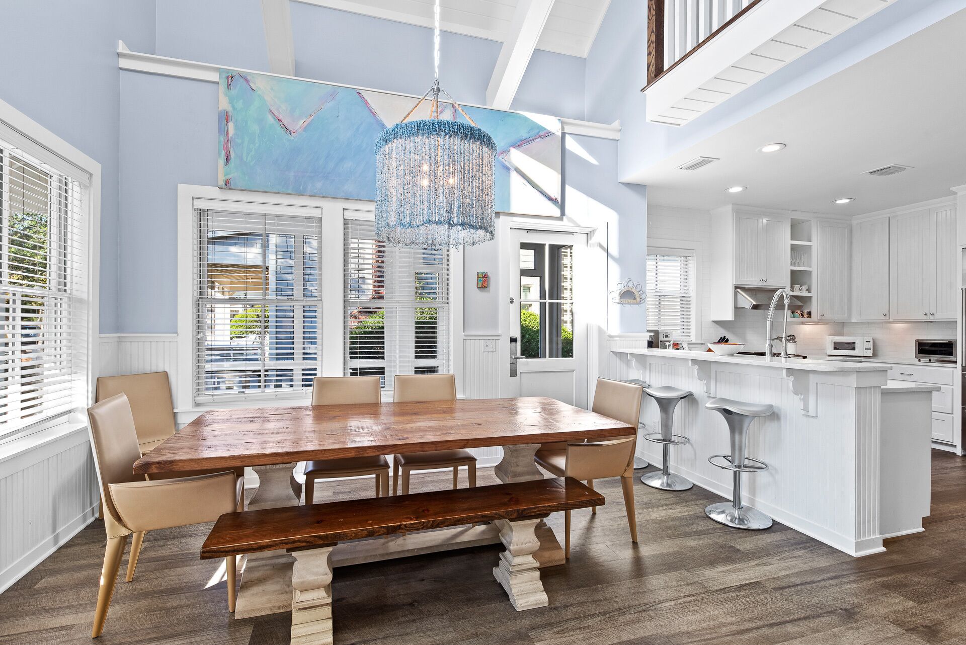 A spacious kitchen with white cabinetry, a central island with stools, and a large dining table with chairs.