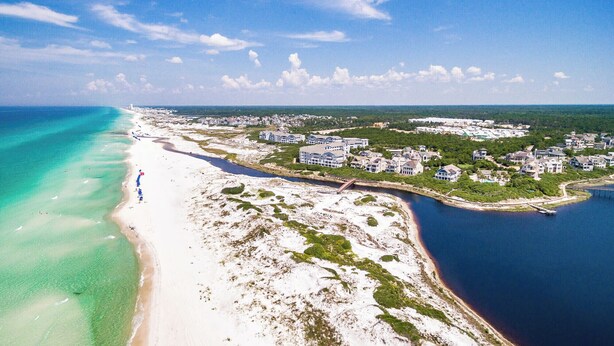 An aerial view of a coastal area with a beach, a bridge, and residential buildings. - Luxury Watersound Getaway with Golf Cart (Watersound)