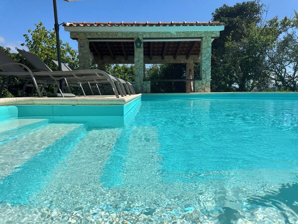 A clear swimming pool with a stone structure in the background.