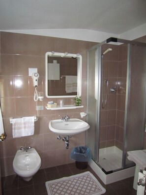 A bathroom with a sink, bidet, and glass-enclosed shower. - Hotel Alpina (Pinzolo)