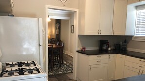 Una cocina con armarios blancos, estufa a gas y cafetera.