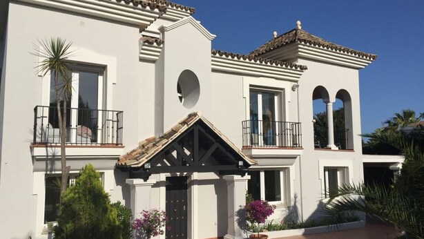 A two-story building with a white facade, multiple balconies, and a tiled roof. - 5 bedroom villa located in the heart of the golf valley. Perfect for families! (Andalucía)