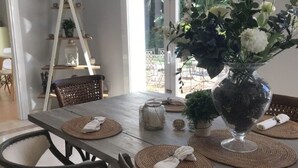A dining area with a wooden table, woven placemats, wicker chairs, and a vase with flowers. - 5 bedroom villa located in the heart of the golf valley. Perfect for families! (Andalucía)