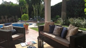 An outdoor patio with wicker furniture, a pool, and a pergola. - 5 bedroom villa located in the heart of the golf valley. Perfect for families! (Andalucía)