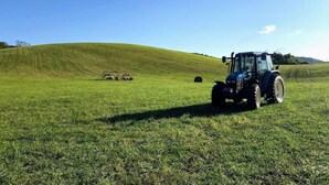 A tractor on a grassy field with a clear sky.