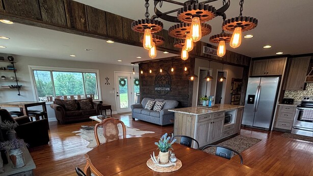 A spacious dining area with a large wooden table, surrounded by chairs, and a chandelier overhead.