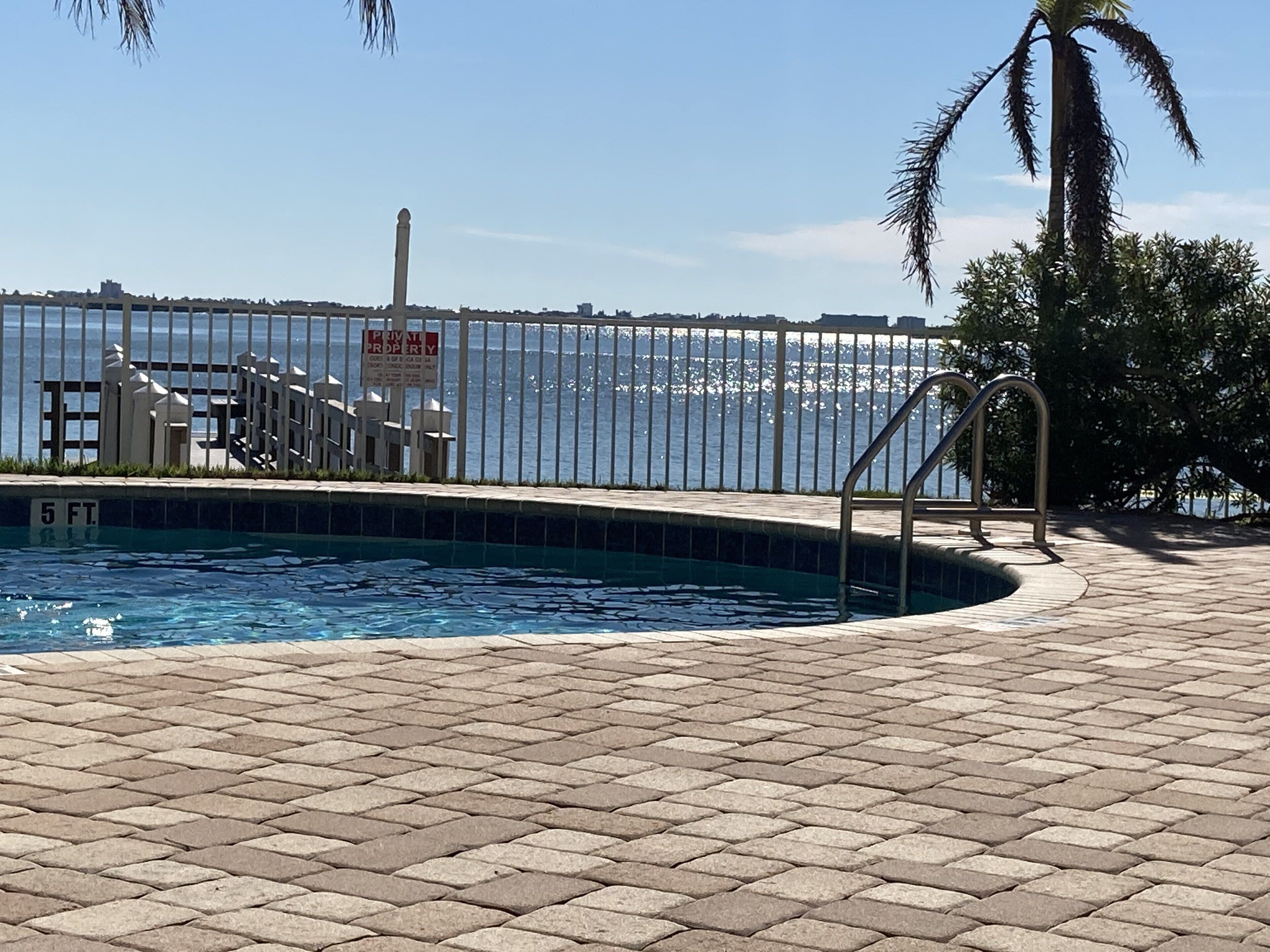 A swimming pool with a view of the ocean, a private property sign, and a palm tree.