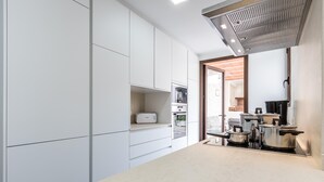 A modern kitchen with white cabinetry, a built-in oven, and stainless steel pots on the counter. - BUGERA. Beautiful restored house in Pollensa (Pollensa)