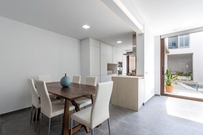 A modern kitchen with white cabinets, a wooden dining table, and a large island. - BUGERA. Beautiful restored house in Pollensa (Pollensa)