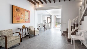 A spacious living area with a dining table, two armchairs, a coffee table, and a staircase with a white railing. - BUGERA. Beautiful restored house in Pollensa (Pollensa)
