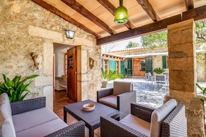 A stone-walled patio with wicker furniture, a hanging light fixture, and a view of the street.