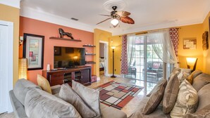 Un salon avec un canapé, un téléviseur et un ventilateur de plafond.